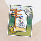 Crafters Companion The Great Outdoors Clear Acrylic Stamp Set Explore card featuring a cyclist and nature-themed signs.